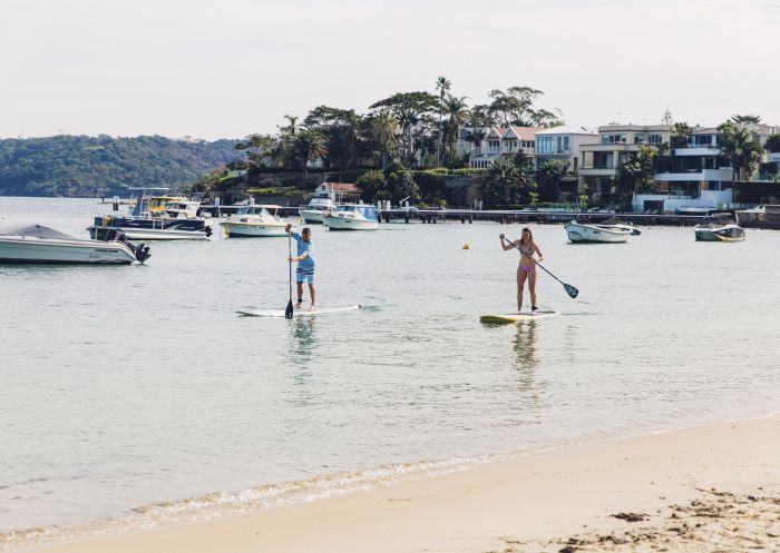 Couple enjoying a morning of stand up paddleboarding at Watsons Bay in Sydney's eastern suburbs