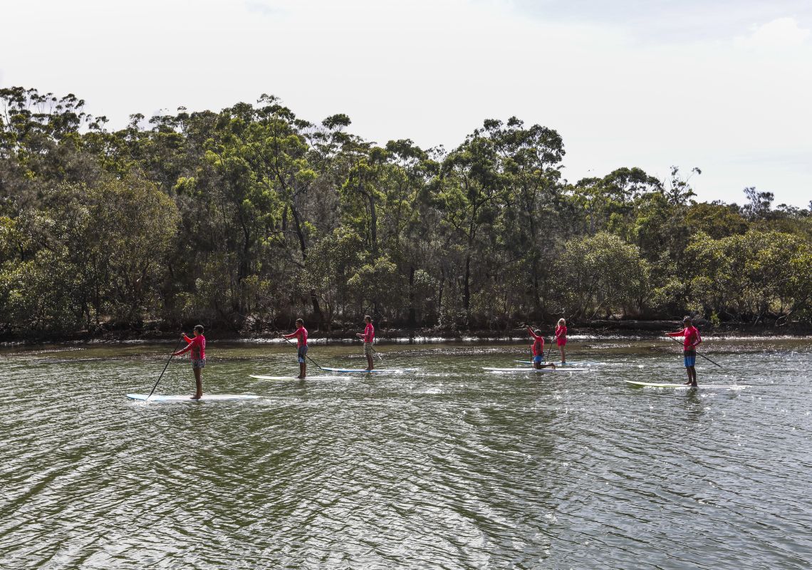 Group enjoying a stand-up paddleboarding tour with Wajaana Yaam Gumbaynggirr Adventure Tours at Moonee Creek, Coffs Harbour, North Coast