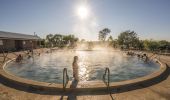 A woman steps into the steaming water at the Artesian Bore Baths, Lightning Ridge