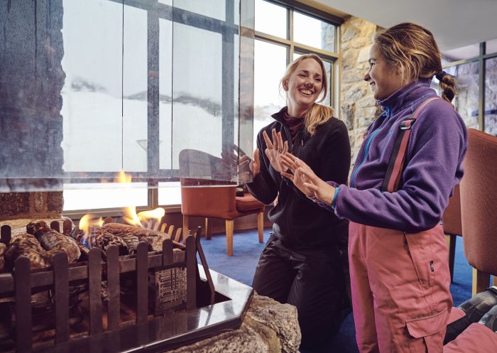 A mother and daughter enjoying the warm fireplace at Snow Gums Restaurant, Perisher.