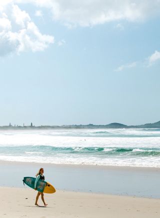 Surfer walking along Broken Head Beach, Byron Bay