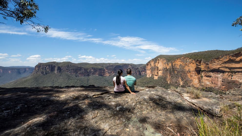 Couple enjoying views of the Grose Valley, Blackheath along the Grand Canyon Walking Track in the Blue Mountains