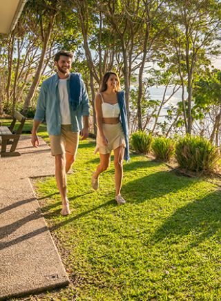 Couple walk through back garden by the beach at Mildenhall cottage in Byron Bay, North Coast